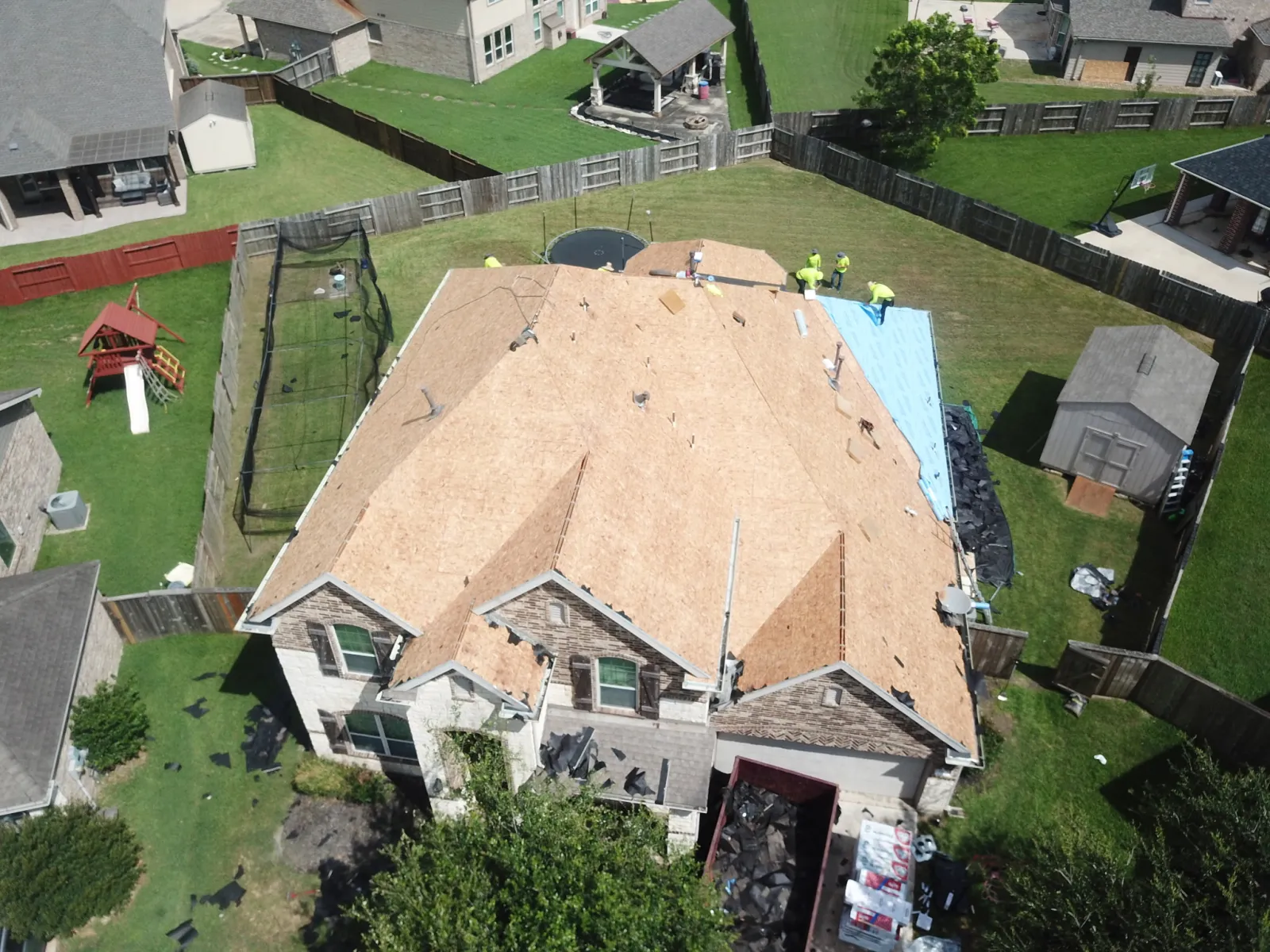 A Now Roofing crew working on an opened roof deck during a repair in Baytown, Texas