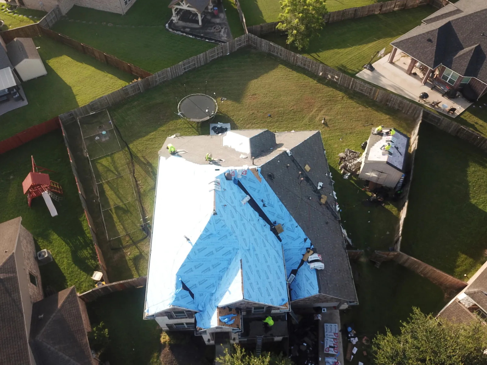 A Now Roofing crew tarp secured over a storm-damaged roof in the Greater Houston area, seen from above